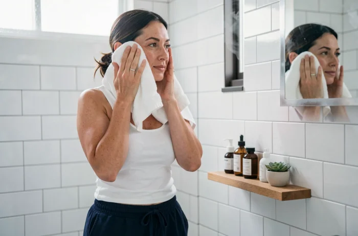Maman prenant soin d'elle dans une salle de bain moderne avec des produits de beauté naturels sur une étagère en bois